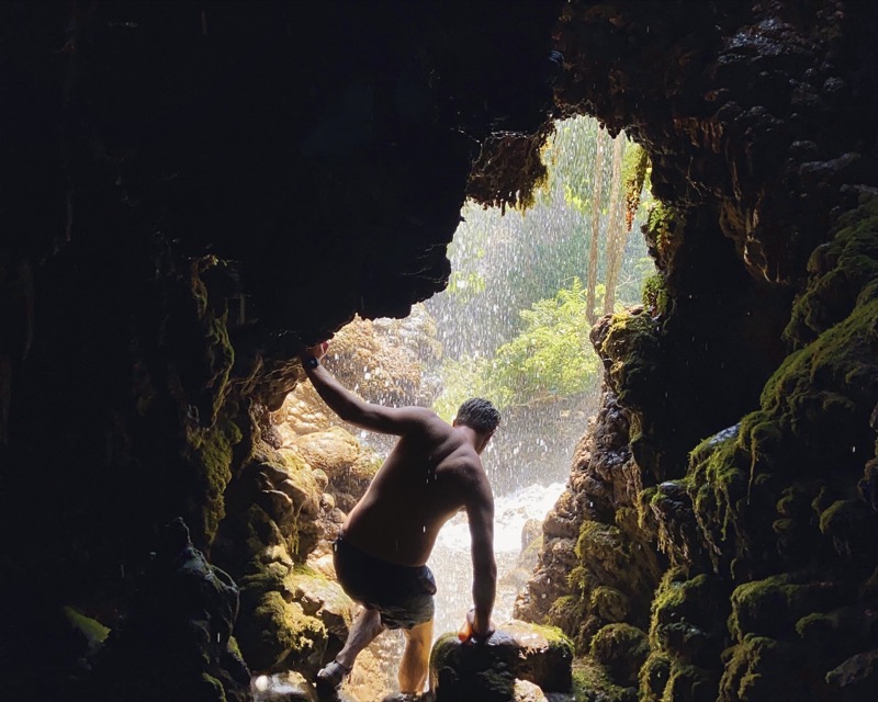 Man spelunking in waterfall cave in Lombok, Indonesia